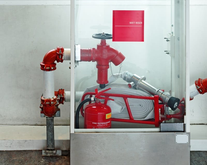 Emergency security kit - fire hydrant, water supply valve, fire extinguisher in a glass box. Indoor safety.